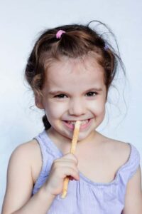 Photo of young girl using a Miswak toothbrush from 